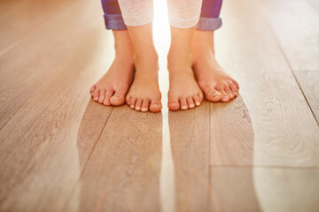 Family, feet and person with child, standing and kid for unity, parenting and together. Barefoot, house and wooden floor or care, support and help in love, background and childhood learning to walk