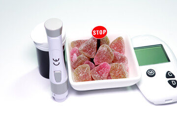 stop sugar concept for diabetic, fruits candy with blood glucose testing equipment on a isolated white.