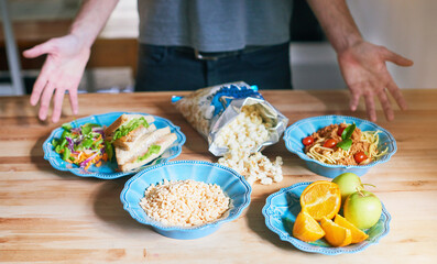 Man, healthy and food on table in kitchen for options of nutrition breakfast, diet and wellness as vegan for weight loss. Male person, meal prep and fruit, vegetable or popcorn as organic snack