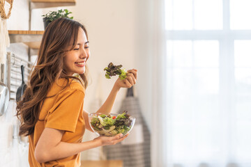 Portrait of beauty body slim healthy asian woman eating vegan food healthy with fresh vegetable salad in kitchen at home.diet, vegetarian, fruit, wellness, health, green food.Fitness and healthy food