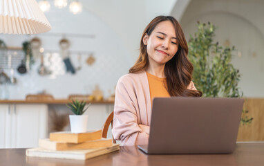 Young smiling asian woman relax using laptop conference work,learning education,study online,webinar podcast,creative woman looking at screen, shopping, online marketing at home