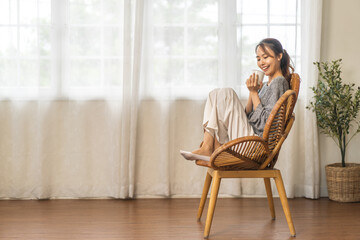Fototapeta premium Portrait of smiling happy cheerful beauty pretty asian woman relaxing drinking and looking at cup of hot coffee or tea.Girl felling enjoy having breakfast in holiday morning vacation on bed at home