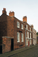 street of old traditional red brick Georgian houses on a cobbled road in Chester England