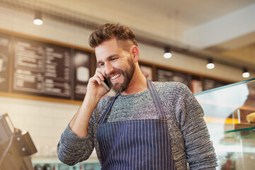 Happy, man and barista with phone in cafe or restaurant for communication on online order, sales and discounts. Smile, owner and contact with customer for e commerce, check list and menu update - Powered by Adobe
