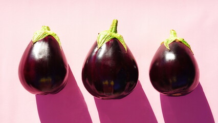 Three Fresh Eggplants On Pink Background Bright Light