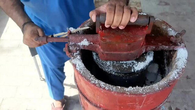 A man rotates an ice cream machine by hand. How to make Qalfa. Manual Kulfa Making Machine in Pakistan. Beautiful 4K Footage.