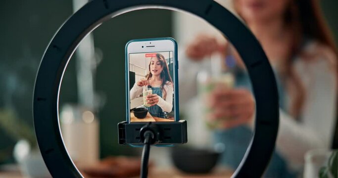 Woman, influencer and phone with tutorial on smoothie for diet, natural nutrition or vegetarian drink at home. Female person, nutritionist or vlogger in live recording for healthy beverage or recipe