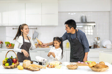 Portrait of enjoy happy love asian family father and mother with little asian girl daughter child play and having fun cooking food together with baking cookie and cake ingredient in kitchen