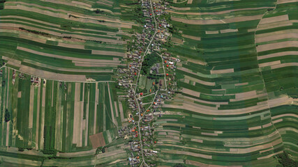 Wide green yellow fields and agricultural village looking down aerial view from above, A long thin...