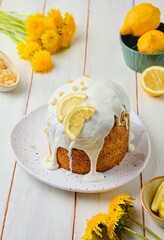 Cake with lemon filling and poppy seeds, covered with sugar icing, on a ceramic plate on a light concrete background. Baking recipes with poppy seeds.