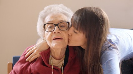 Granddaughter embracing and kissing her grandmother in a geriatric
