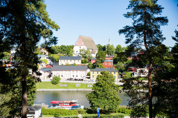 Porvoo, Finland. Townscape of Old town of Porvoo. Picturesque wooden houses on a river slope. Stone Medieval lutheran cathedral on a hill. Warm sunny summer day in nordic country.
