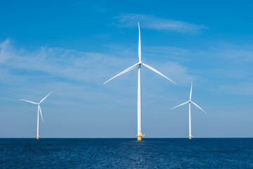 A group of wind turbines rise majestically from the ocean off the coast of Flevoland, Netherlands,...
