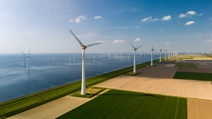 A line of wind turbines gracefully turning in the breeze beside a vast expanse of water, creating a...