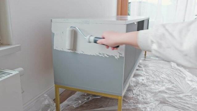 Caucasian Woman Renovating Wooden MDF Furniture Using Painting Roll 