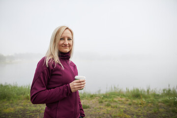 Confident mature woman enjoys a peaceful morning with coffee in misty weather