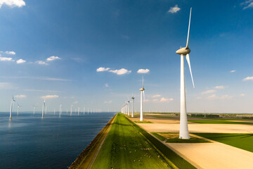 A row of elegant wind turbines stand tall next to a serene body of water, harnessing the power of...