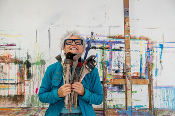 older gray haired mature happy smiling artist woman proud artist, in her fifties with grey hair and...