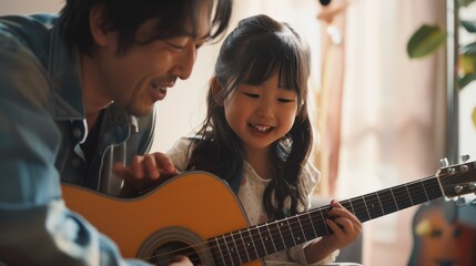 Asian father teaching his daughter to play the guitar in their living room, creating a happy and joyful atmosphere in family.