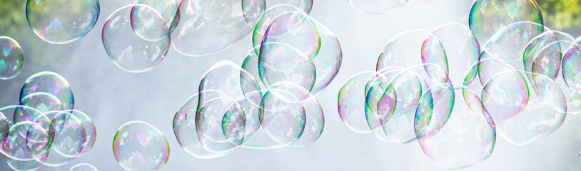 soap bubbles close-up on a background of sun and greenery, abstract background, positive mood, holiday, carelessness, banner format