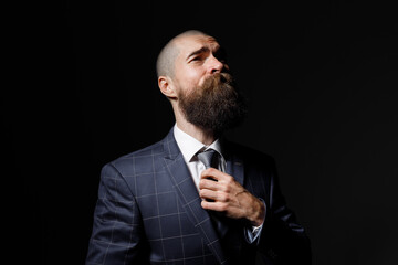Brutal guy on dark background. attractive man with a beard in a classic suit.