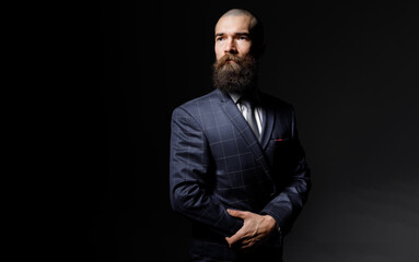Brutal guy on dark background. attractive man with a beard in a classic suit.