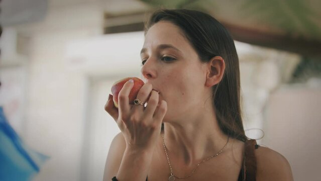 Woman eating an apple at the market