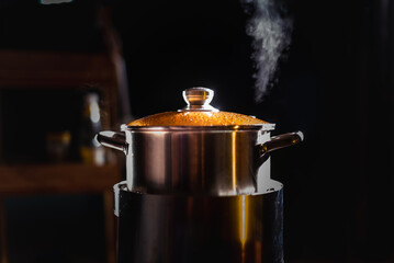 A boiling pot shoots up steam as a chef cooks food in a restaurant.