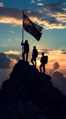 Group of people in silhouette with flag standing triumphantly on mountain top, embodying teamwork and achievement concepts