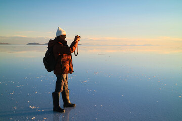 Traveler Shooting Photos on the Amazing Mirror Effect of Uyuni Salt Flats at Sunset, Bolivia, South...