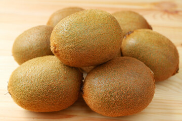 Closeup of pile of fresh kiwi fruits on wooden table