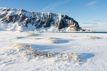 An arctic snowy beach by the Arctic Ocean on a sunny winter afternoon, Berlevåg, Norway