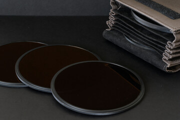 Close up of three circular magnetic neutral density filters alongside a protective carry pouch