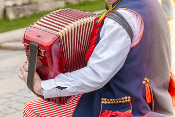 A street musician in traditional Krakow clothes plays the harmonium