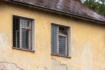 An old abandoned building with crumbling plaster and barred windows.