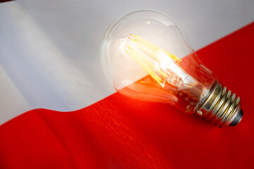 A glowing light bulb lying in the middle of the Polish flag, Concept, Energy prices in Poland