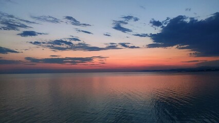 Sunlight on the sea after sunset. Pink and red colors. Some clouds