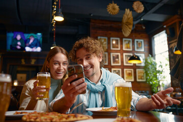 Young people looking into smartphone while rest in bar