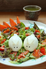 Plate of delectable green salad with a pair of bunny shaped hard boiled eggs