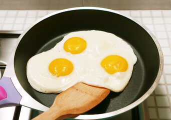 Three of chicken eggs sunny side up being fried in a pan