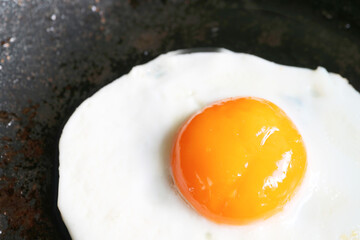 Closeup of a sunny side up egg being fried in a pan