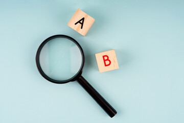 Magnifying glass and alphabet A and B on soft blue background