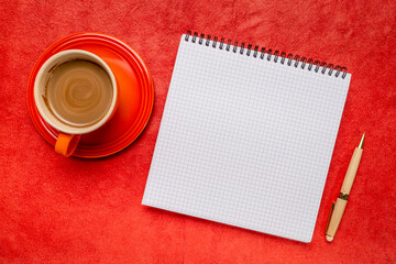 blank spiral notebook with ruled paper, flat lay with coffee on red textured art paper