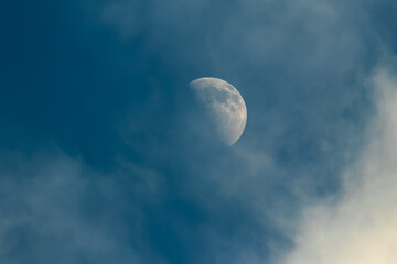 The moon in the evening sky with clouds.