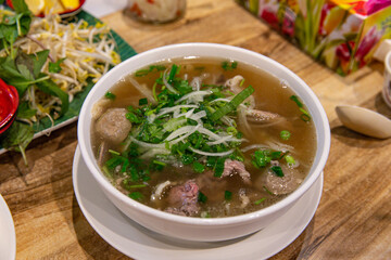 Classic Pho Bo with Beef Slices, Garnished with Basil and Lime in a Flavorful Vietnamese Broth