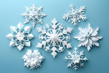A beautiful winter scene of paper snowflakes in various shapes and sizes. The snowflakes are arranged on a blue background, creating a delicate and festive display.