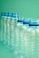 Group of plastic bottles for recycling placed in a row on a green background.