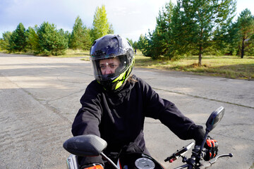woman motorcyclist in a helmet, motorcycle gloves, motorcycle boots on a motorcycle close-up
