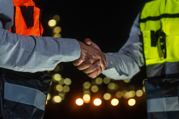 Night scene. Close up of Asian man petrochemical engineers shaking hands together after going...