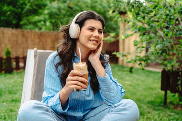 Fototapeta premium One young caucasian woman is enjoying music on her wireless headphones while laying on easy chair in her backyard